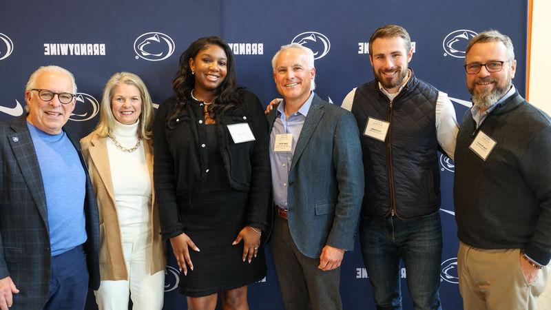 student with advisory board members pose for a photo